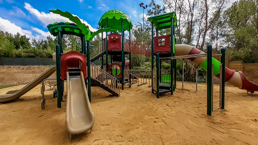 Aire de jeux extérieure avec toboggan, balançoire et enfants jouant