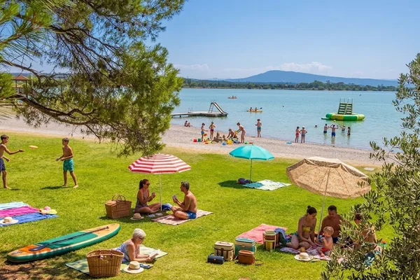 Familles sur la plage herbeuse du lac de Jouarres à Homps